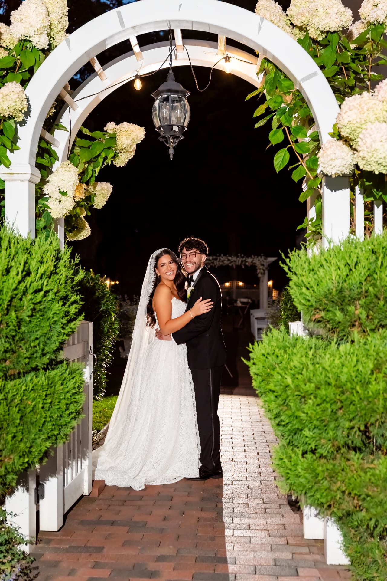 Wedding couple beneath a white floral arch