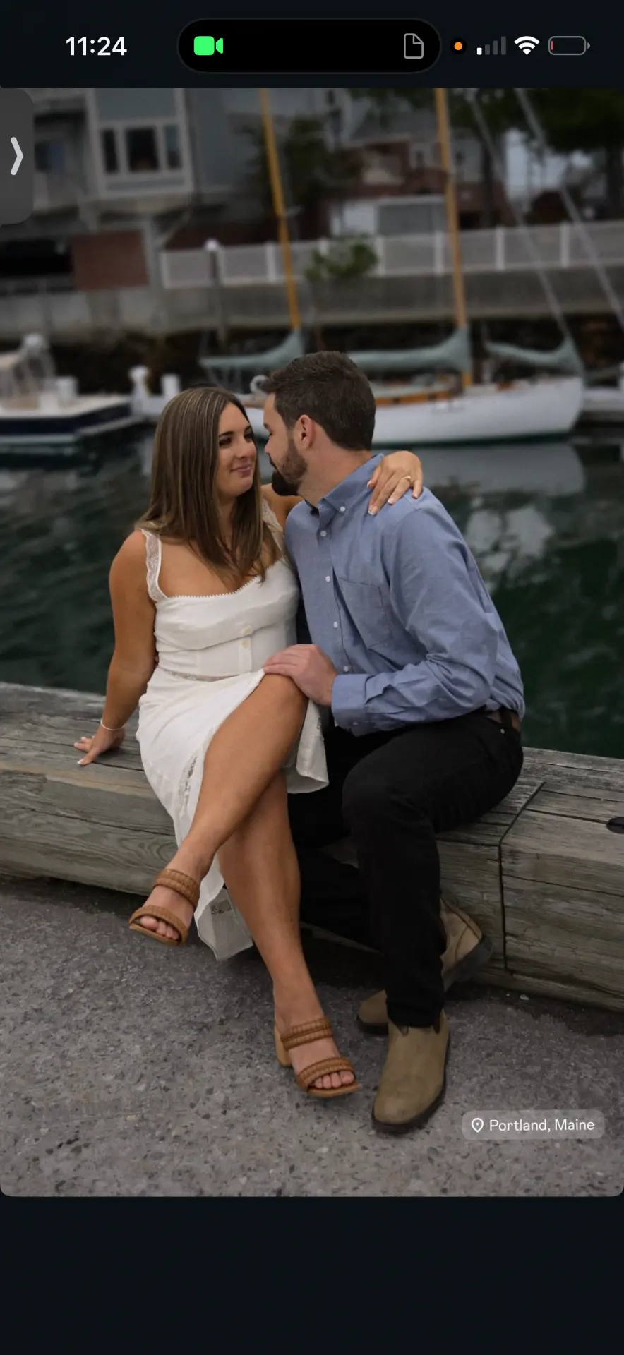 Engaged couple sitting together beside the harbor